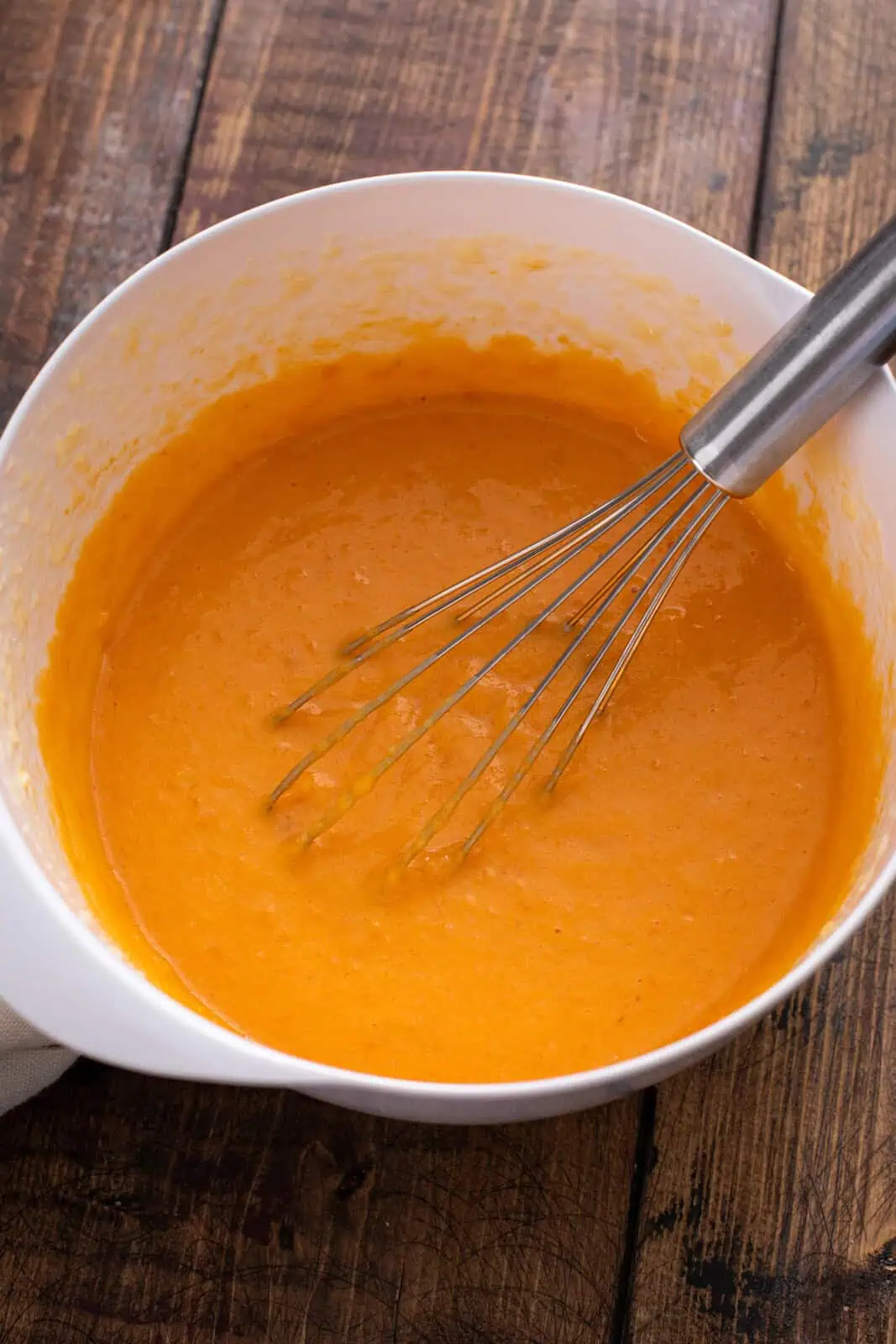 Wet ingredients for sweet potato cornbread whisked in a white bowl.