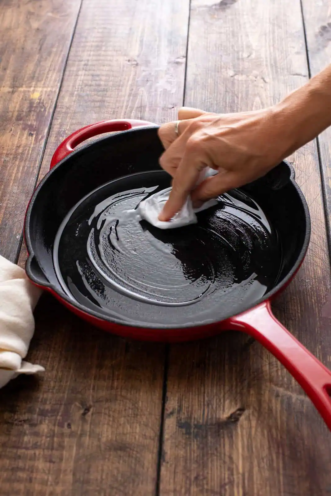 Vegetable oil being rubbed on the inside of a cast iron skillet.