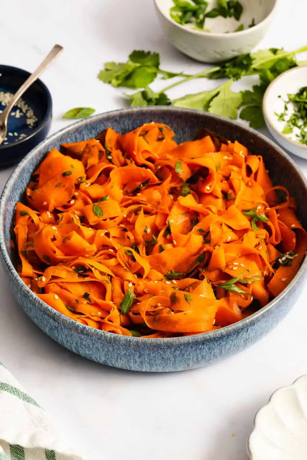 Blue ceramic serving bowl filled with shaved carrot salad.