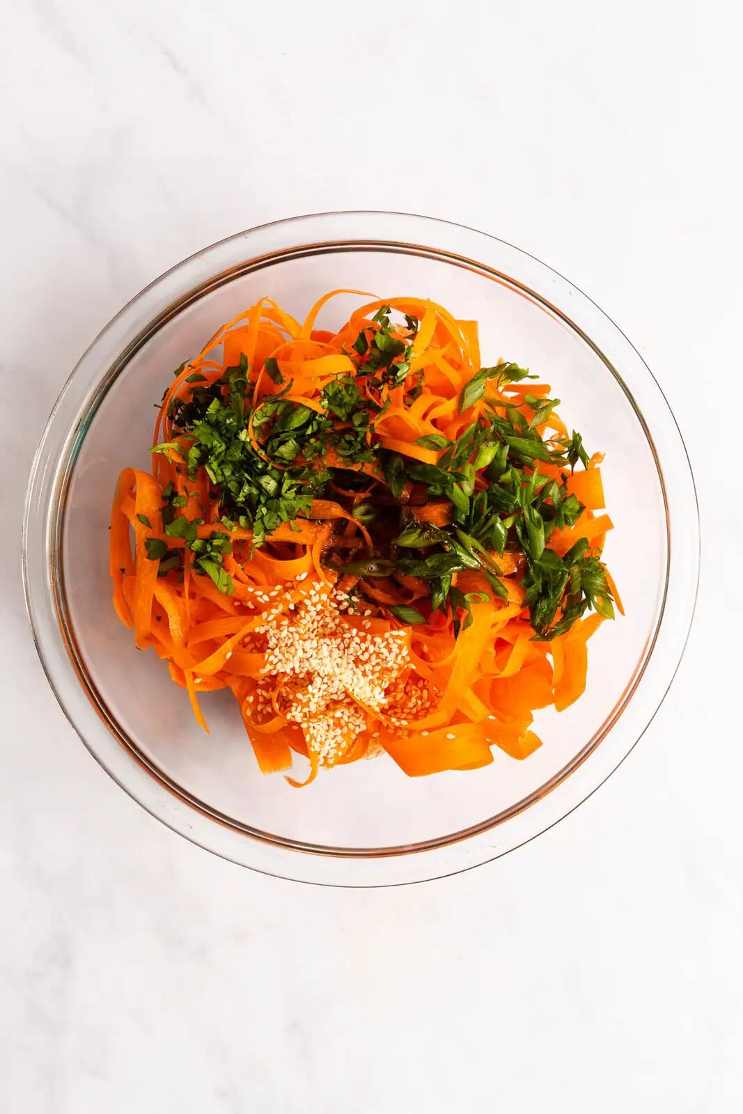 Ingredients for shaved carrot salad added to a glass mixing bowl.