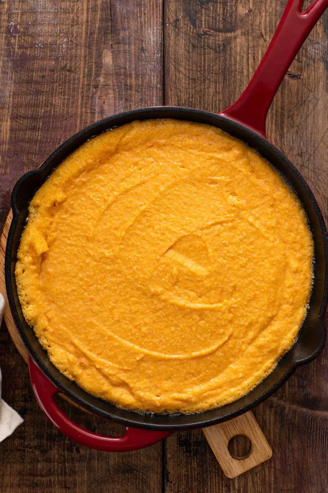 Sweet potato cornbread batter spread into a cast iron skillet.