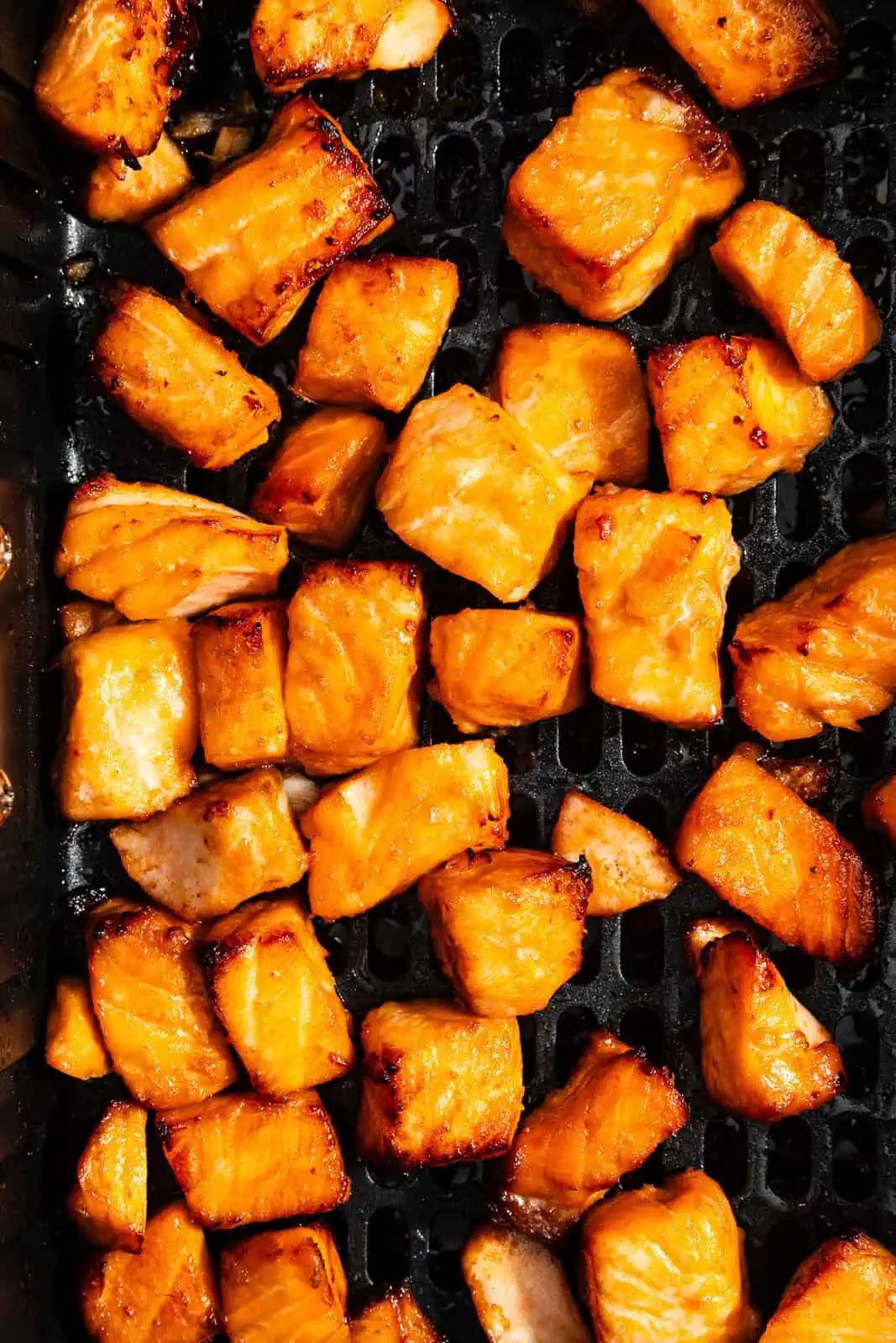 Cooked air fryer salmon bites in the basket of an air fryer.