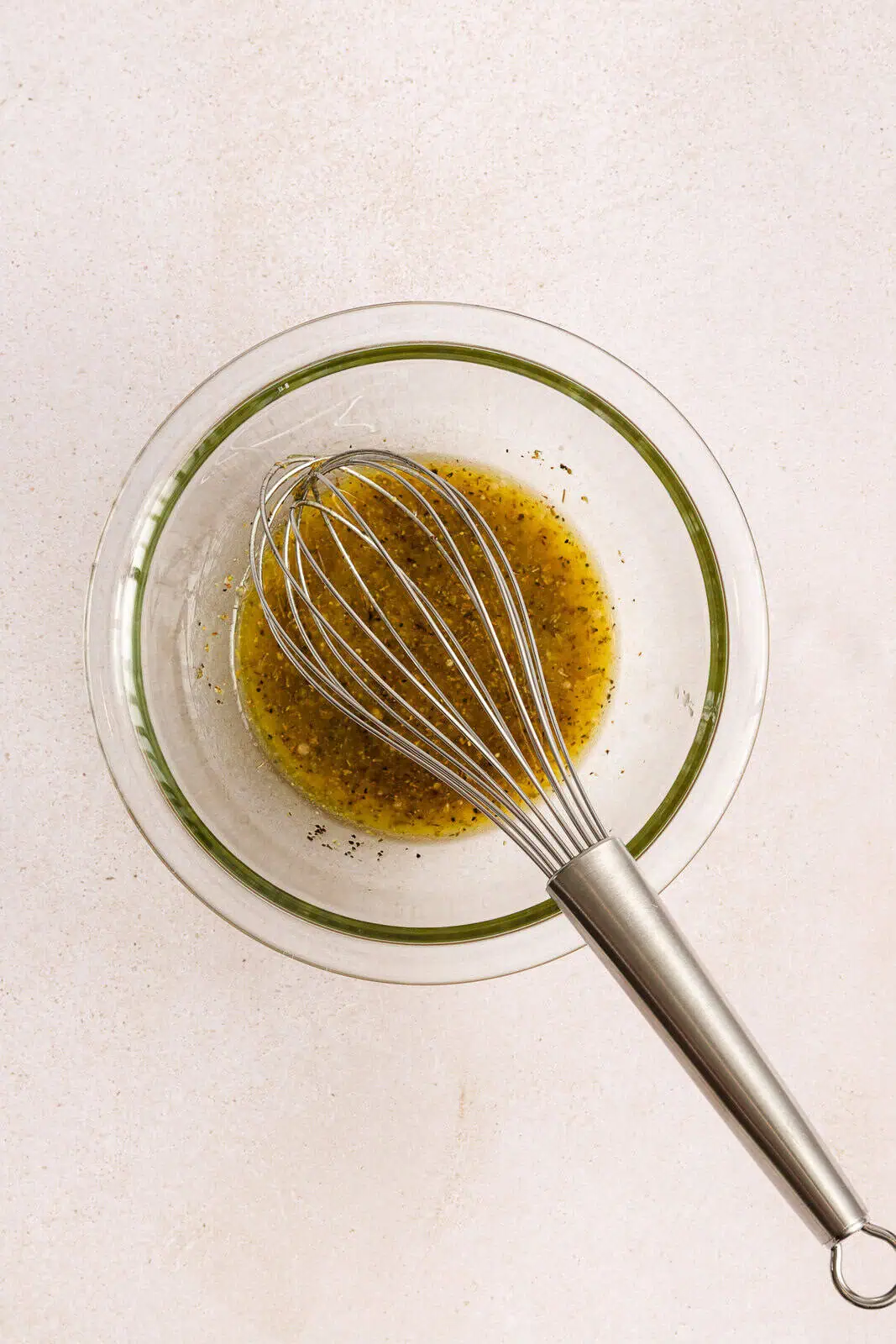 Dressing for cucumber feta salad whisked together in a small glass bowl.