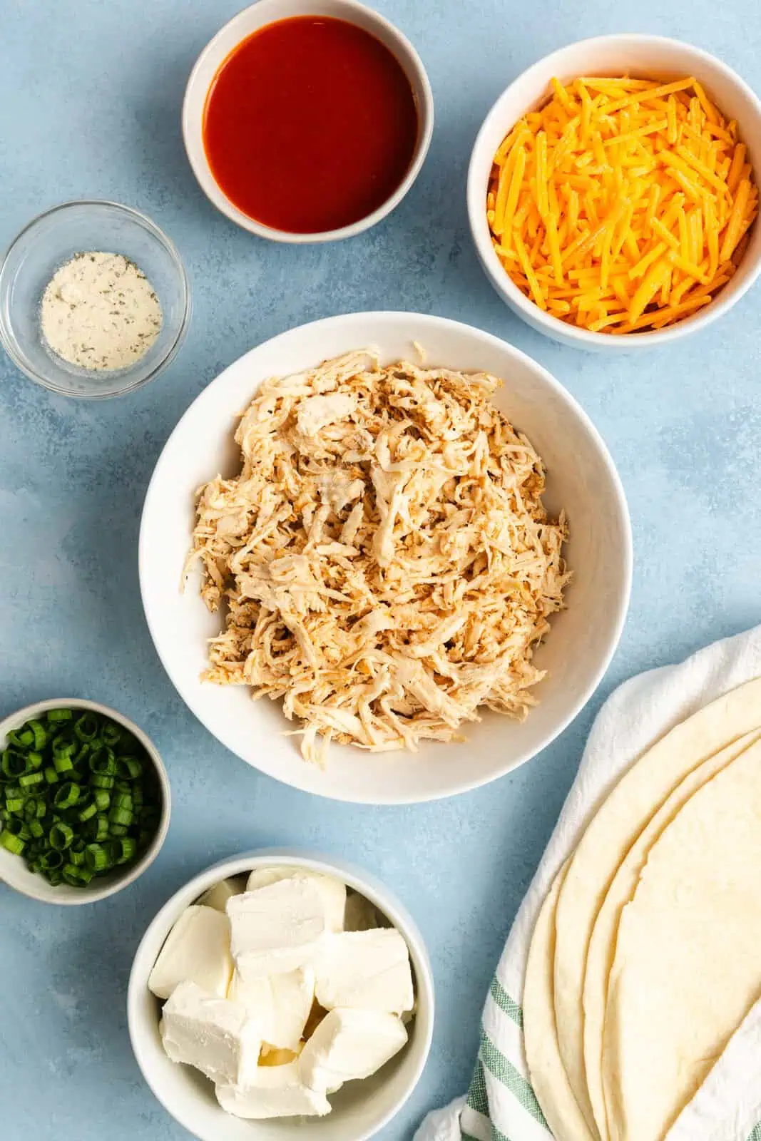 Ingredients for buffalo chicken pinwheels arranged on a countertop.