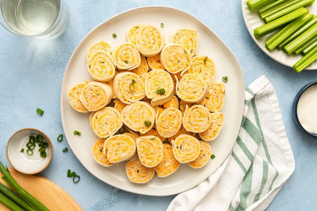 White plater stacked with slices of buffalo chicken pinwheels.