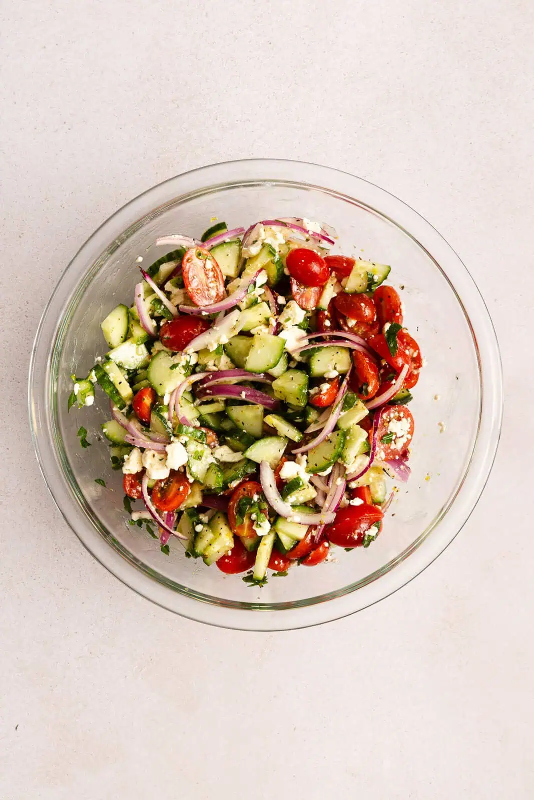 Cucumber feta salad mixed in a glass mixing bowl.