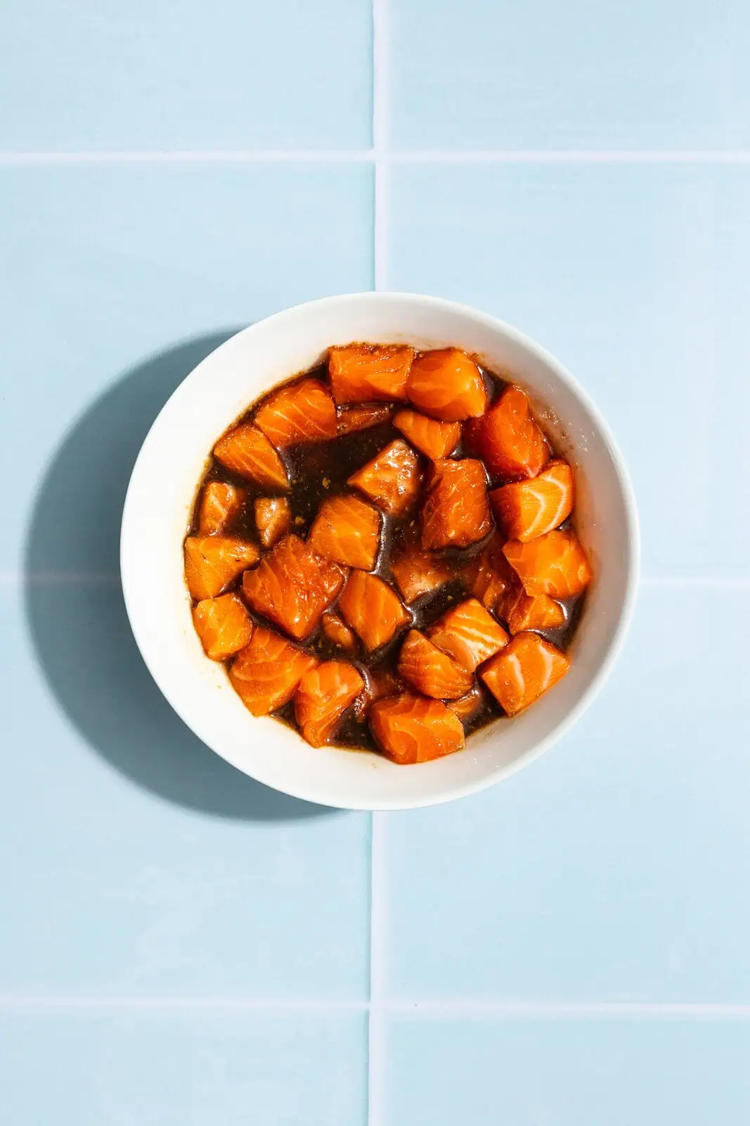 Cubes of fresh salmon in a bowl with an Asian-inspired sauce.