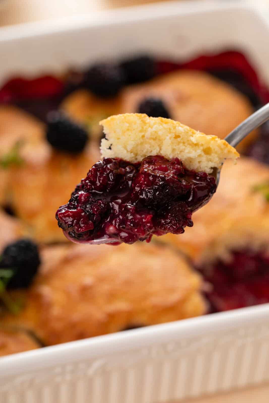 Spoon holding up a bite of blackberry cobbler.