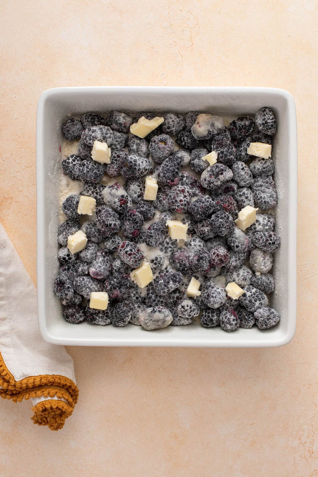 Blackberry cobbler filling mixed in a baking dish, ready to be par-baked.