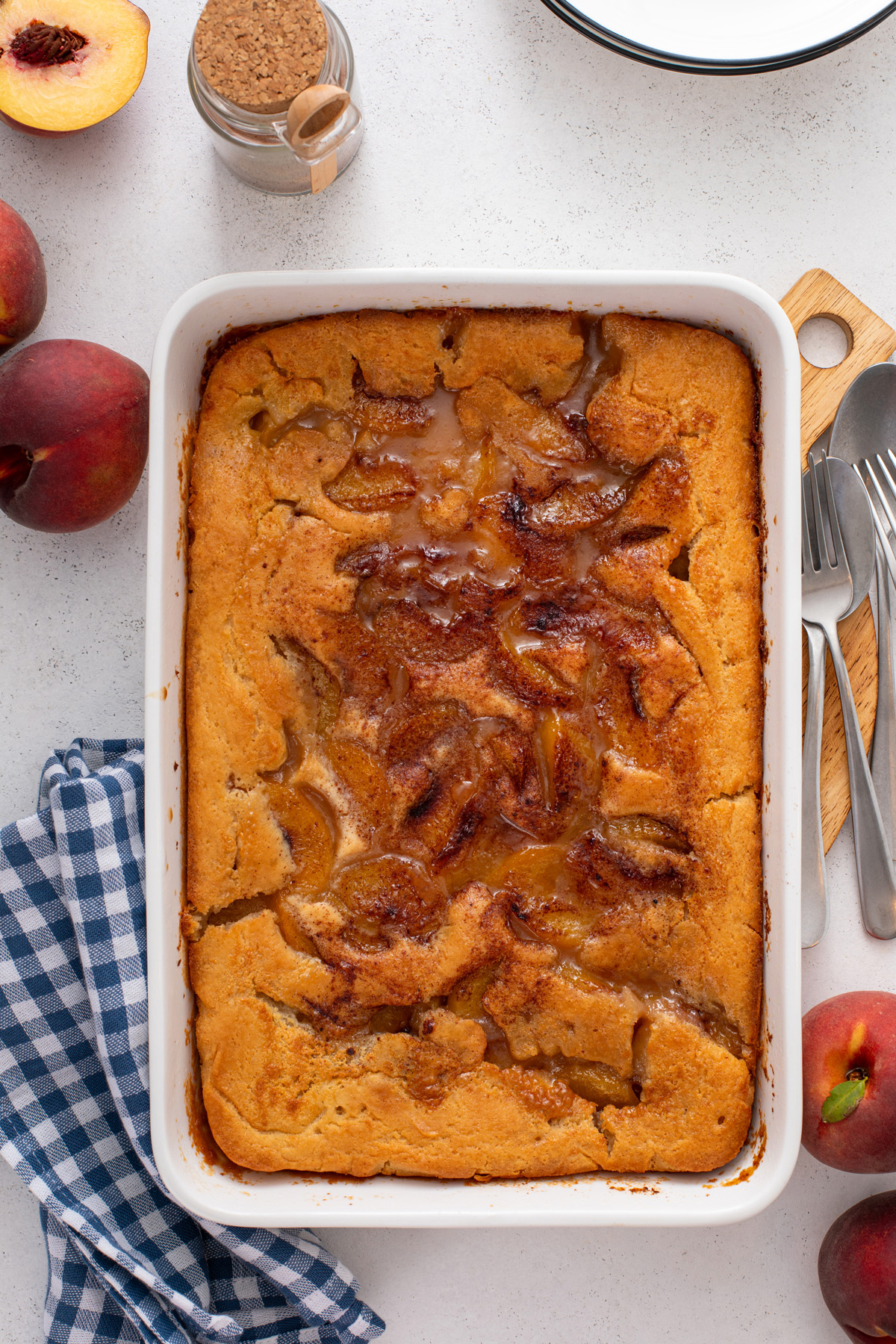 Baked old-fashioned peach cobbler cooling in a white baking dish.