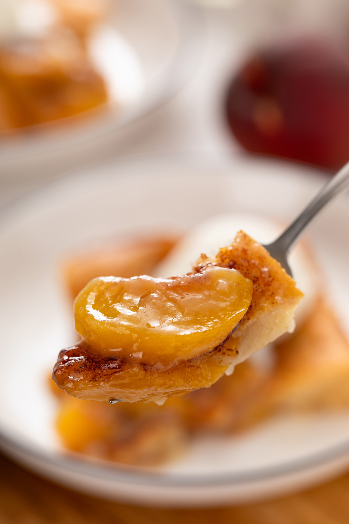 Fork holding up a bite of peach cobbler to the camera.