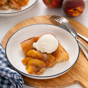 Serving of old-fashioned peach cobbler on a white plate.