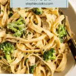 Overhead view of a serving of chicken and broccoli alfredo in a shallow white bowl. Text overlay includes recipe name.