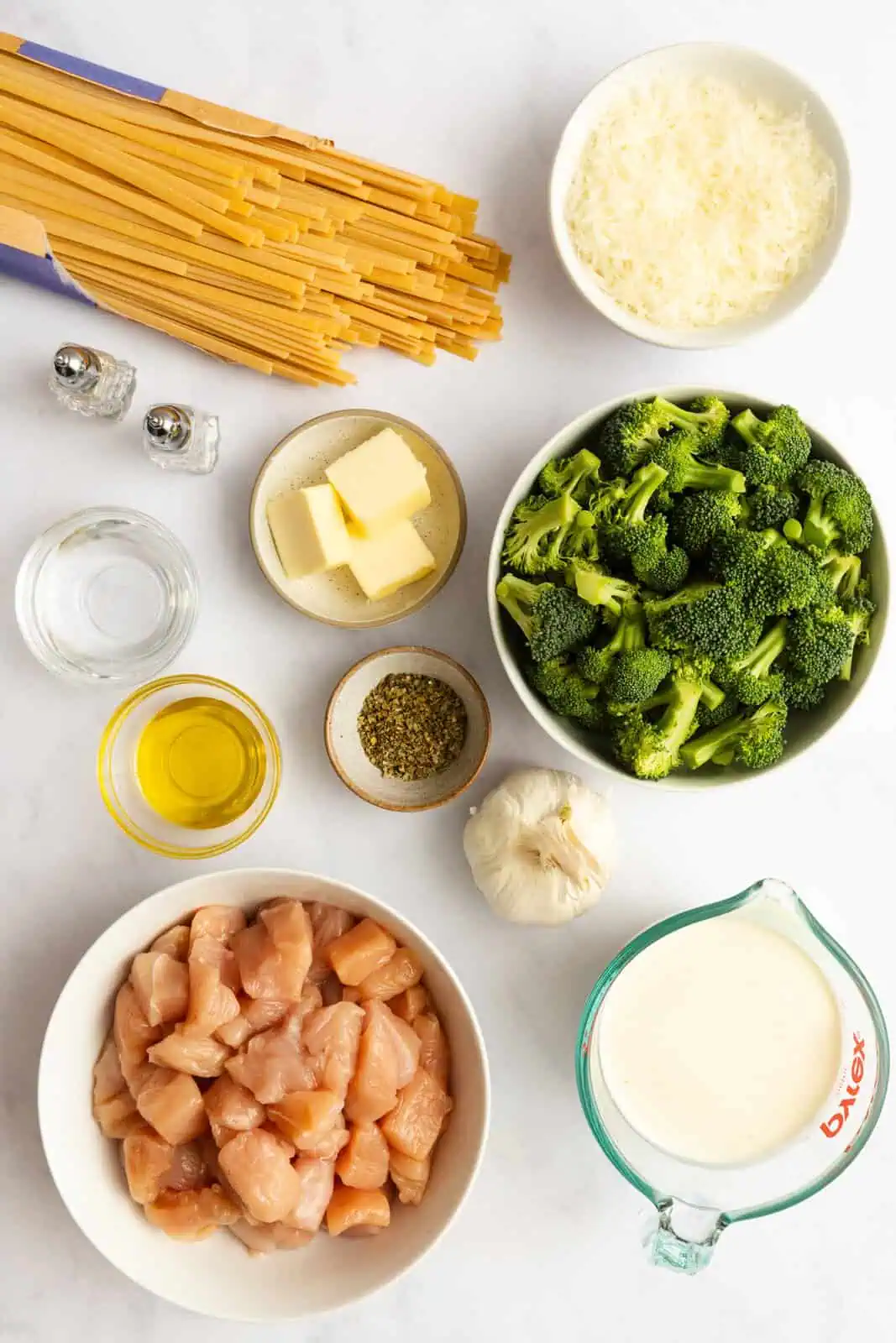 Ingredients for chicken and broccoli alfredo arranged on a countertop.