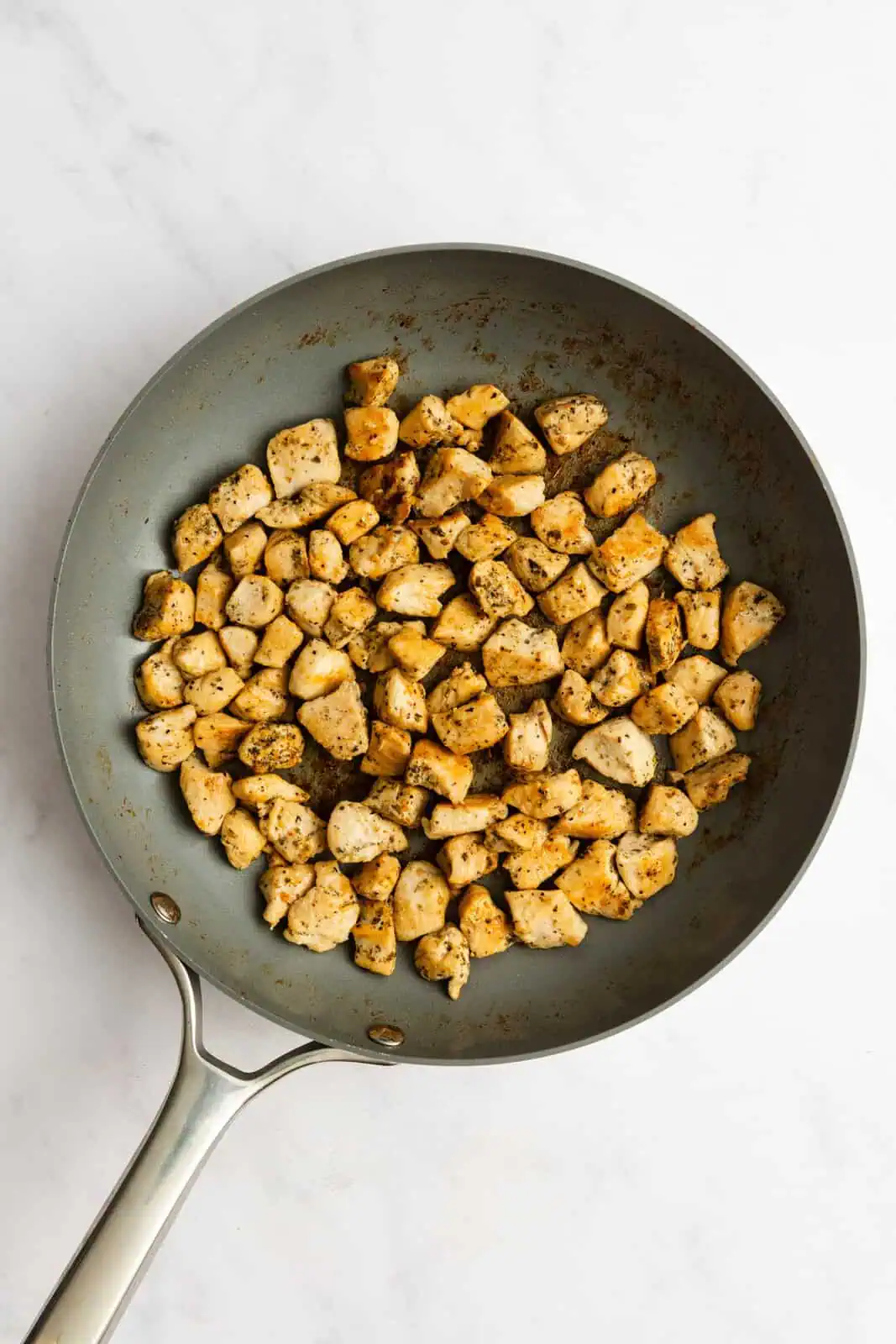 Diced chicken sauteed until golden in a skillet.
