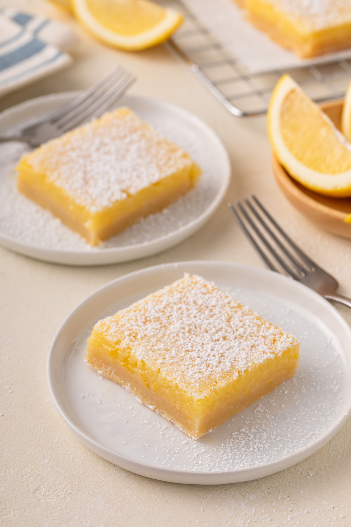 Two white plates, each holding a sliced lemon bar.