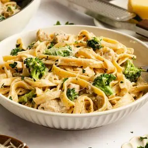 Close up of a bowl of chicken and broccoli alfredo.