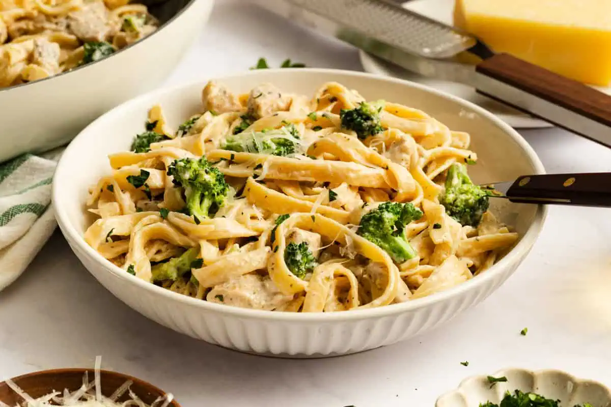 Serving of chicken and broccoli alfredo in a shallow white pasta bowl.