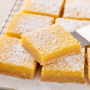 Cake server about to lift up a sliced lemon bar.