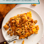 Overhead view of a serving of sweet potato casserole with streusel topping on a white plate next to a rust-orange napkin. Text overlay includes recipe name.