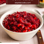 Spoon next to a small bowl of cranberry jello salad on a countertop. Text overlay includes recipe name.