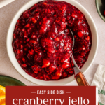 Spoon in a small white bowl of cranberry jello salad. Text overlay includes recipe name.