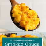 Wooden spoon holding up a serving of smoked gouda mac and cheese above the baking dish. Text overlay includes recipe name.