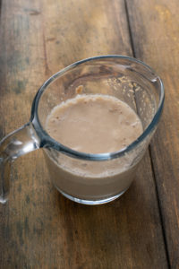 Yeast activated in water in a measuring cup, with the top of the mixture looking foamy.