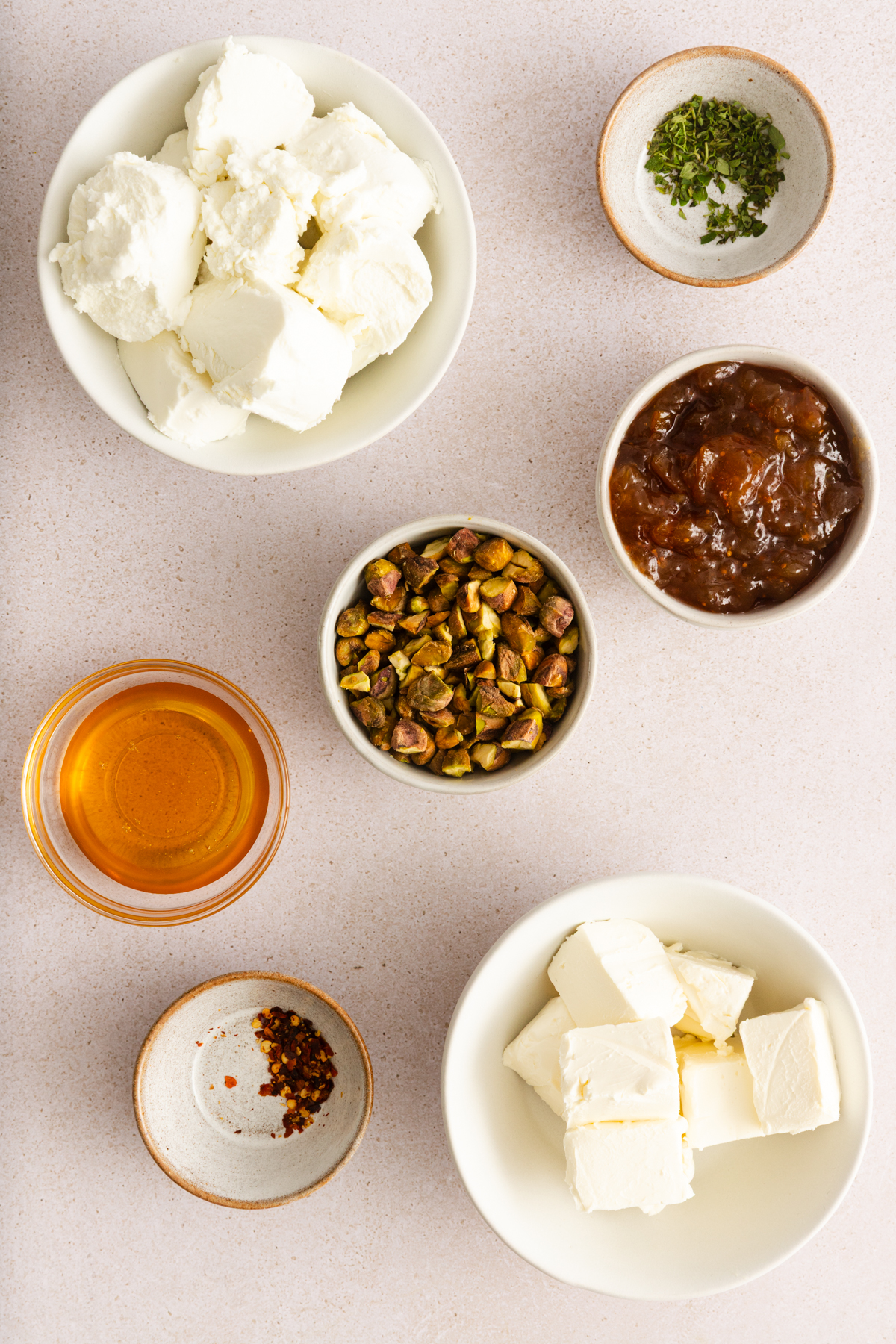 Ingredients for baked goat cheese dip arranged on a countertop.
