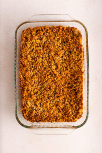 Baked sweet potato casserole with golden-brown pecan streusel topping in a glass dish on a countertop.