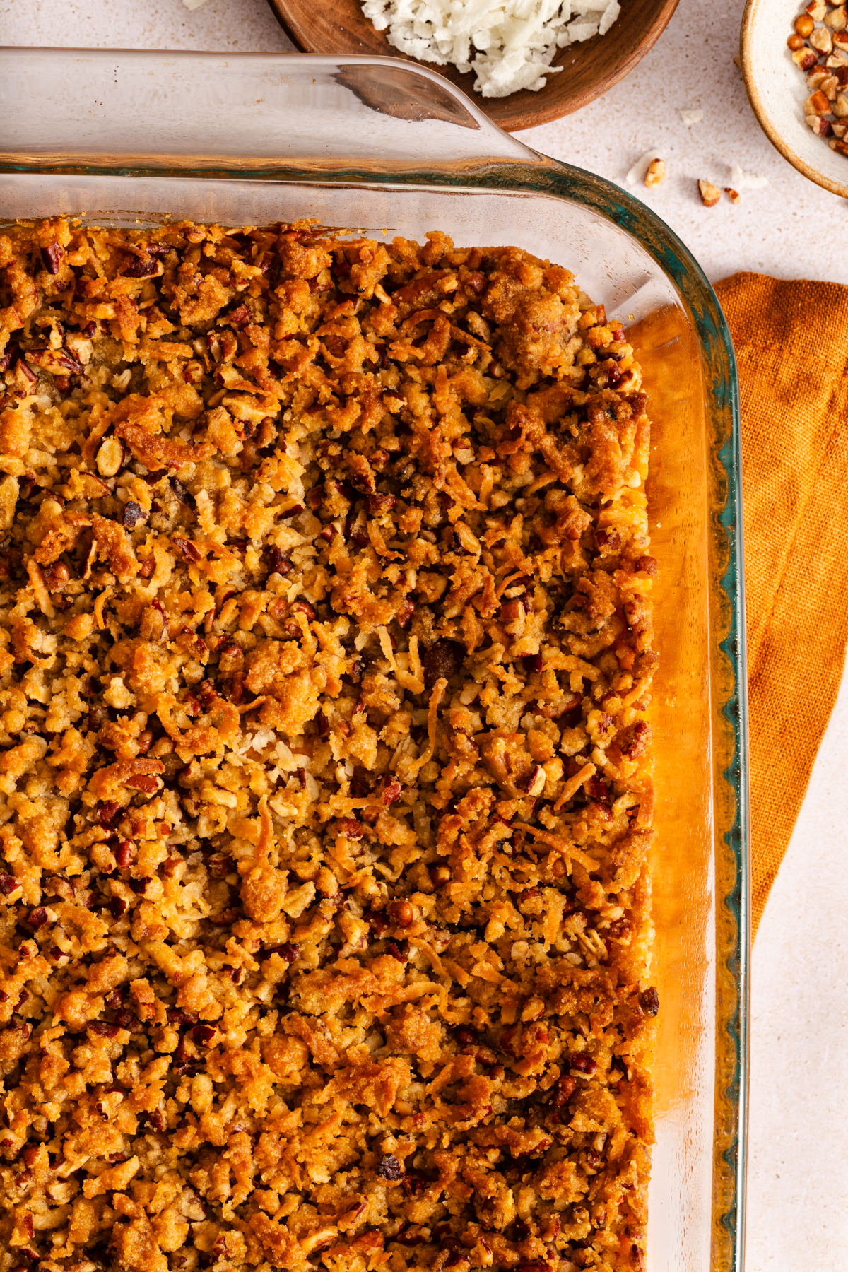 Close up overhead view of baked sweet potato casserole in a glass dish to show the crunchy pecan topping.