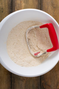 Butter and shortening cut into flour in a mixing bowl, the mixture resembling coarse meal.