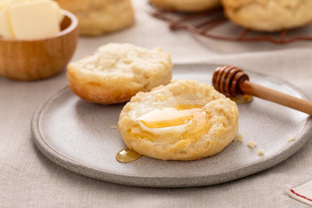 Halved angel biscuit on a plate, topped with butter and honey.