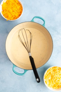 Smoked gouda cheese sauce for mac and cheese whisked in a dutch oven.