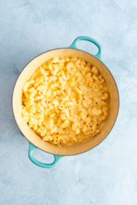 Creamy smoked gouda cheese sauce mixed with cooked noodles in a dutch oven.