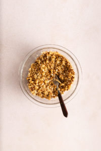Pecan streusel topping stirred together with a fork in a glass bowl.