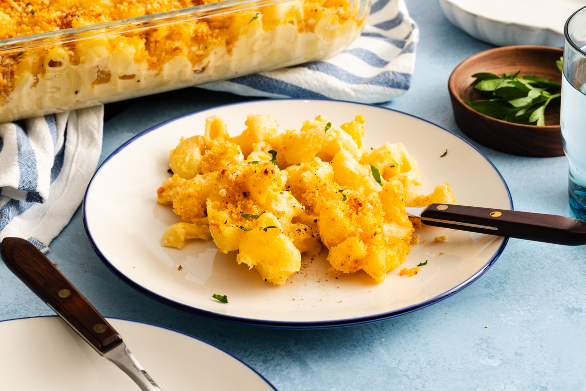 Serving of smoked gouda mac and cheese with a fork on a white plate.
