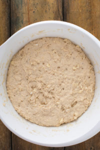 Risen angel biscuit dough in a white bowl, with the top of the dough high up on the sides of the bowl.