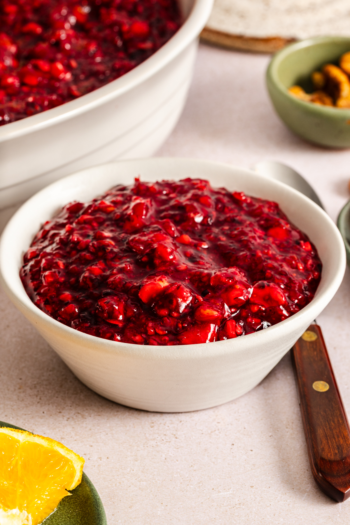 Spoon next to a small bowl of cranberry jello salad on a countertop.
