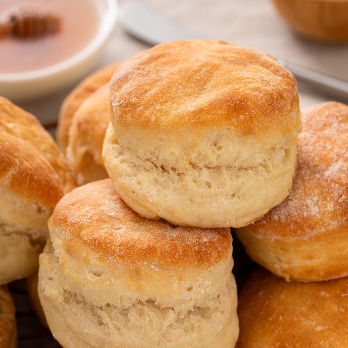 Stacked angel biscuits with a bowl of honey in the background.